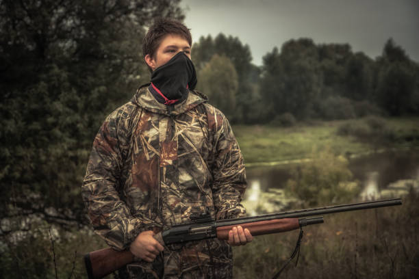 teenager hunter with face mask and gun during duck hunting season - boyhood imagens e fotografias de stock