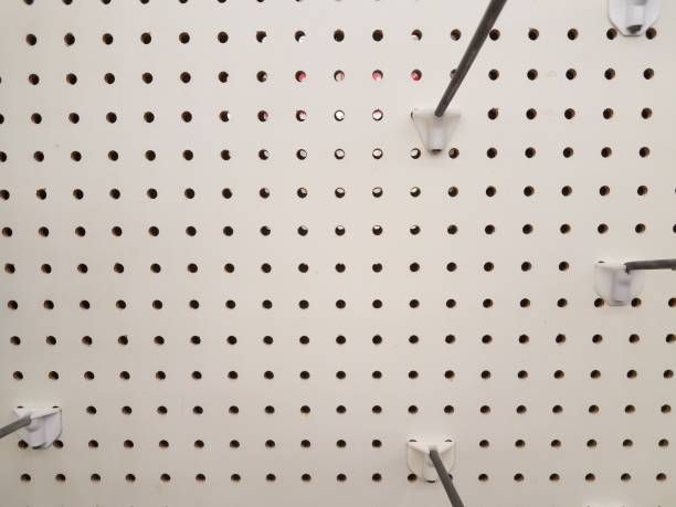 empty white pegboard or wall with holes and metal hooks