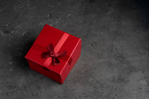 istock Red square holiday gift box against a dark background 1169025204