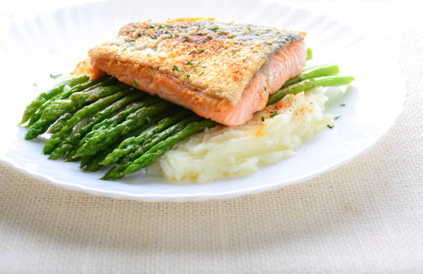 istock Grilled salmon garnished with asparagus and herbs and mashed potatoes, served on white plated.