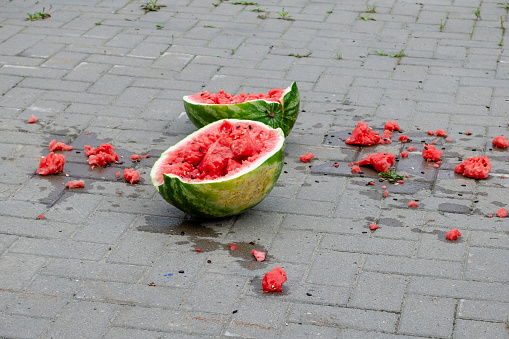 Broken into two large pieces of watermelon on the cobblestones