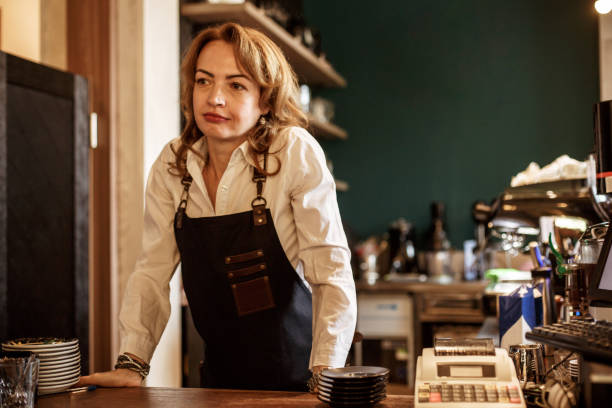 istock Smiling barista standing behind a bar 1169041236