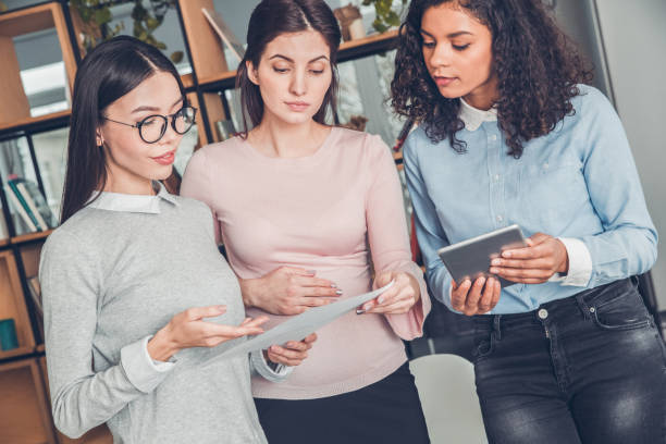 istock Female startupers working together at office standing looking at contract discussing concentrated 1169041535