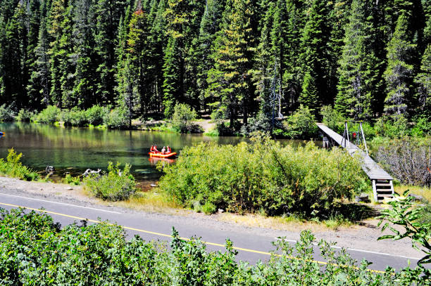 Truckee River Recreation and Walking Bridge Tahoe City, California, USA - August 18, 2019: This is the Truckee river flowing from Lake Tahoe at this point it is running alongside highway 89. This time of the year this is a very popular area for water related recreation such as the incidental people floating along in the raft, there is a walking bridge crossing that river at this point for anyone that wants to go to the other side of the river, at this point on this beautiful August day the sight looks very exciting. truckee river photos stock pictures, royalty-free photos & images