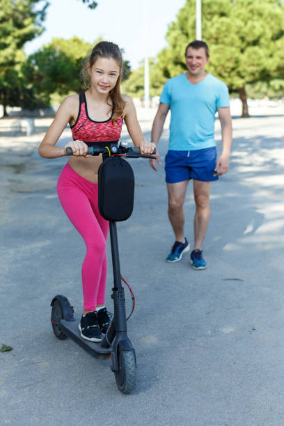 istock Girl riding kick scooter with father 1169047748