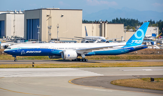 This image is of a Boeing 777x doing a high speed taxi test at Seattle Everett airport. The Boeing 777X is the latest series of the long-range, wide-body, twin-engine Boeing 777 family from Boeing Commercial Airplanes. The 777X will feature new GE9X engines, new composite wings with folding wingtips, greater cabin width and seating capacity, and technologies from the Boeing 787. The 777X was launched in November 2013 with two variants: the 777-8 and the 777-9. The 777-8 provides seating for 365 passengers and has a range of 8,690 nmi (16,090 km) while the 777-9 has seating for 414 passengers and a range of over 7,525 nmi (13,936 km). The -9 is expected to fly in 2020 with deliveries the same year.