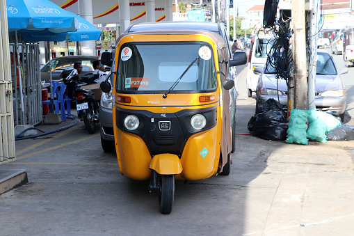 Phnom Penh, Cambodia, August 17, 2019 : Tuk Tuk or Taxi tricycle in yellow color on the road, Lifestyle of traffic in Phnom Penh. It is a three-wheeled motorized vehicle used as a taxi.