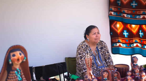 Santa Fe Indian Market 2019: Native Artist with Clay Figures Santa Fe, NM, USA: A native artist in her booth with sculpted clay figures at the 2019 Santa Fe Indian Market. The outdoor market spreads out around the historic Santa Fe Plaza, showcasing North American Indigenous arts and culture. More than 900 artists from hundreds of tribes participate in the two-day event; visitors number about 100,000. kachina doll stock pictures, royalty-free photos & images