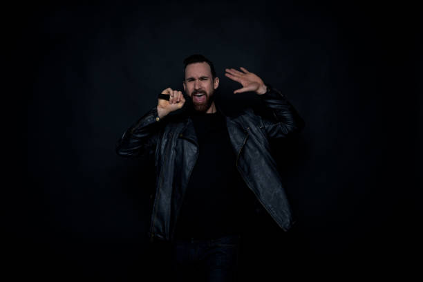 istock Handsome man singing with microphone and wearing leather jacket 1169055461