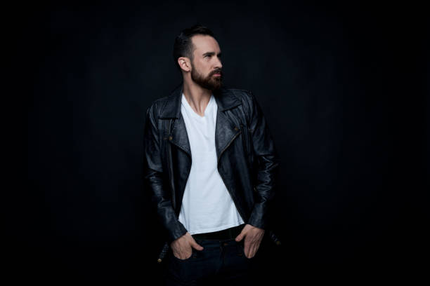 istock Handsome man wearing leather jacket and white shirt on black background 1169055488