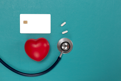 Red heart, stethoscope and pills on wooden background