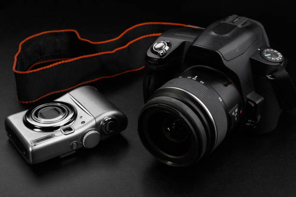 istock Compact amateur and professional dslr cameras on black background 1169065824