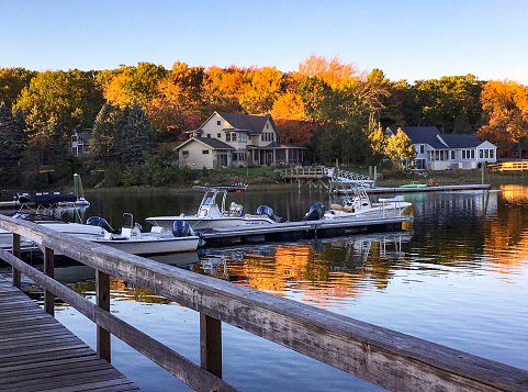 Portsmouth, NH / USA - Oct 16, 2018: Beautiful autumn landscape of docked boats, waterfront homes, autumn leaves, and colorful reflections in the water.