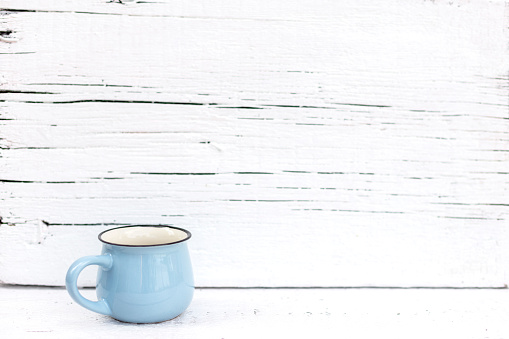 Enameled mugs in retro style on an old wooden background. Selective focus.