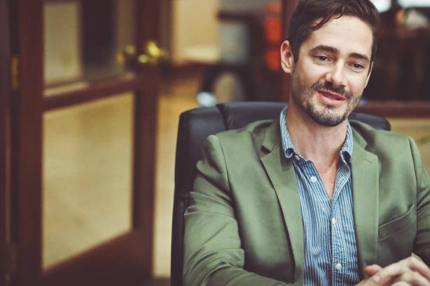 istock Busi ess people sitting at a conference table smiling and having a meeting 1169069562