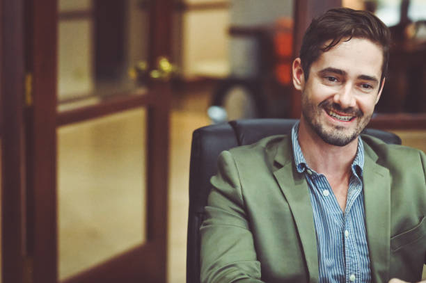 istock Busi ess people sitting at a conference table smiling and having a meeting 1169070258