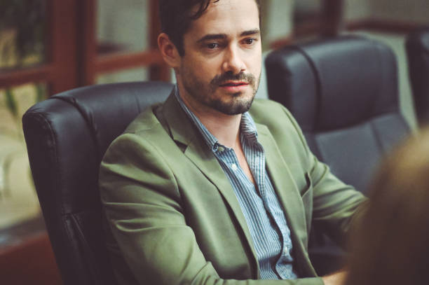 istock Busi ess people sitting at a conference table smiling and having a meeting 1169070287