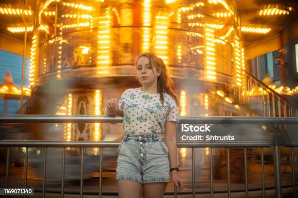 Teenage Girl Stands Close To A Spinning Carousel Stock Photo - Download Image Now - Long Exposure, Portrait, 12-13 Years