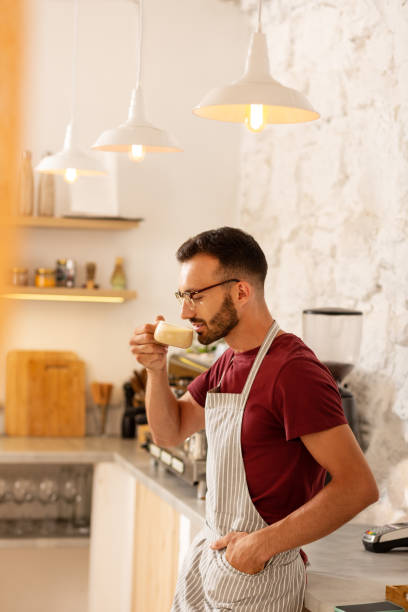 istock Bearded man owning coffee room standing and drinking coffee 1169071578