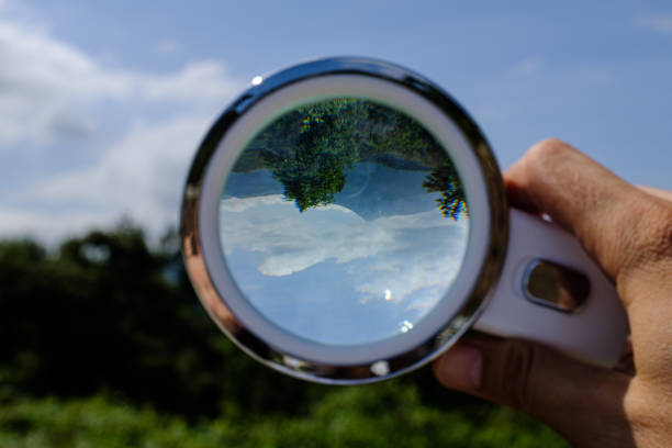istock Handheld Loupe optical magnification effects view upside down on a green and blue nature landscape 1169072865