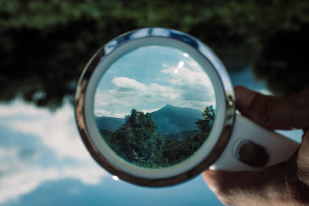 istock Handheld Loupe optical magnification effects view upside down on a green and blue nature landscape 1169072880