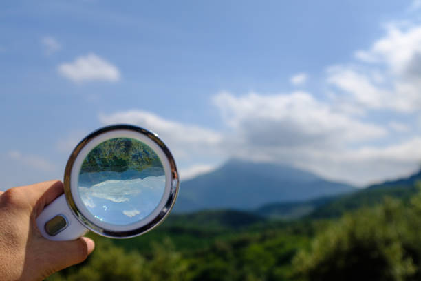 istock Handheld Loupe optical magnification effects view upside down on a green and blue nature landscape 1169072900