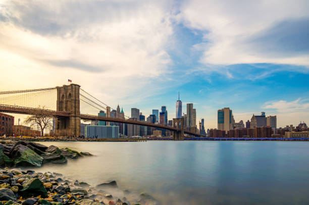 beautiful sence of brooklyn bridge and lower manhattan of new york city in dusk evening. downtown of lower manhattan of new york city and smooth hudson river with sunset light. - skyline new york city brooklyn bridge new york state imagens e fotografias de stock