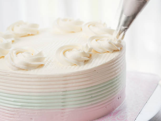 istock Confectioner topping cakes with cream using a pastry bag, 1169078221