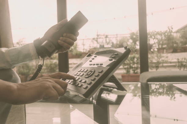 cierre el hombre de mano sosteniendo el receptor de teléfono y marcando un número de teléfono para hacer una llamada usando el teléfono landline para business talk. - telephone old old fashioned desk fotografías e imágenes de stock