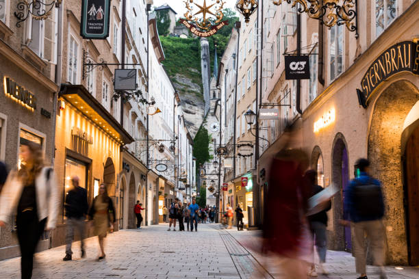 Luxury shops and old town streets illuminated at night in Salzburg, Austria Salzburg, Austria - 7 August, 2019: wide angle color image depicting the old fashioned streets and luxury stores of Salzburg, Austria, illuminated in early evening. Many people and tourists are walking the cobbled streets, exploring the charming atmosphere of this Austrian city. salzburg stock pictures, royalty-free photos & images