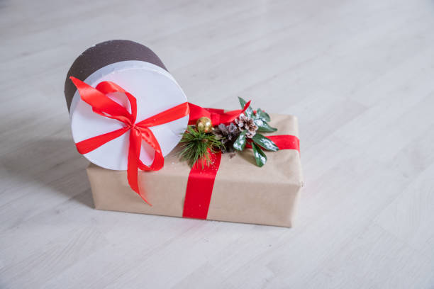 Christmas Presents and Ornaments on Wooden Background regalos de navidad y ornamentos sobre fondo de madera.envueltos regalos de navidad rodados en cálido suelo de madera. presenta en papel artesanal y de colores decorado con arcos de cinta rojas y copos de nieve. navidad y otros días festivos concepto.