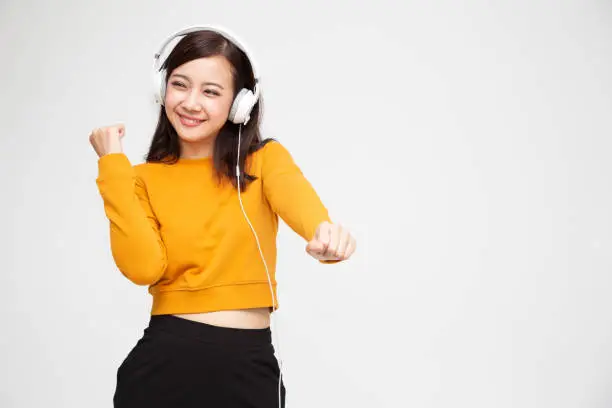 Photo of Asian woman listening music with headphones in playlist song application on smartphone, Hipster young girl concept