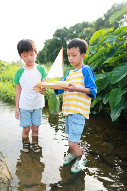 istock Boy plays with toy sailboat in water 1169086189