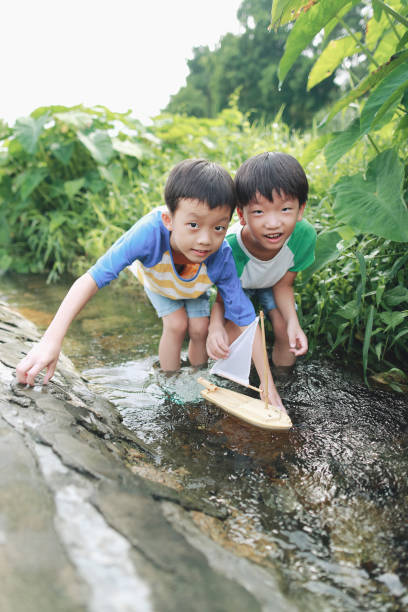 istock Boy plays with toy sailboat in water 1169086210