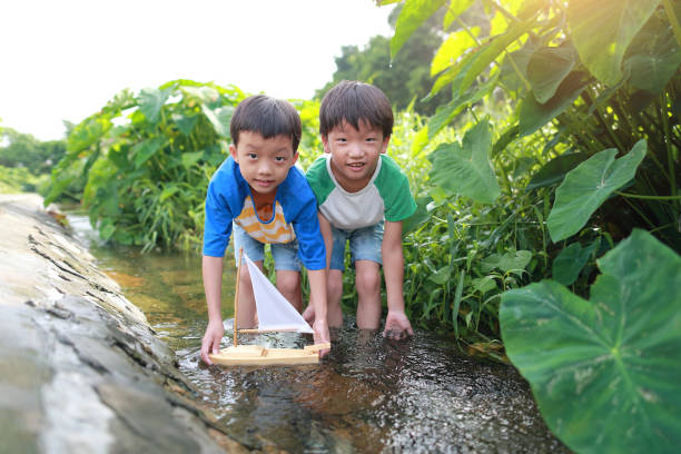 istock Boy plays with toy sailboat in water 1169086268