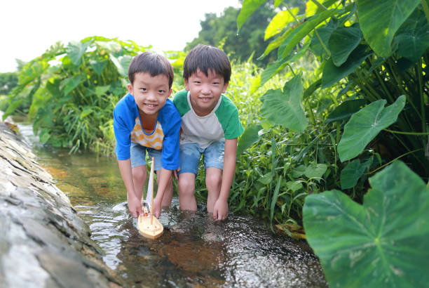istock Boy plays with toy sailboat in water 1169086331