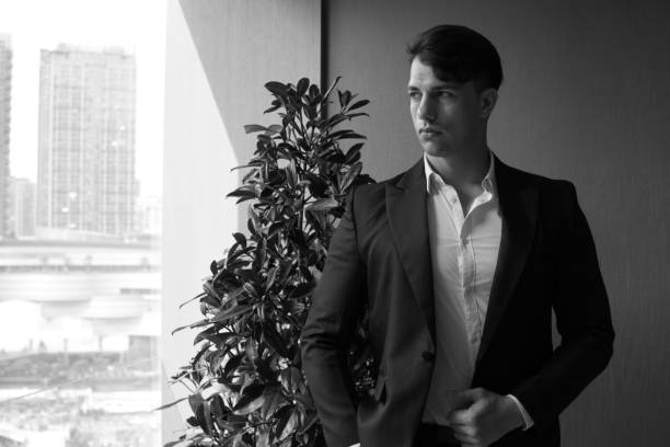 istock Handsome young man in full suit looking away while standing indoors. 1169086718