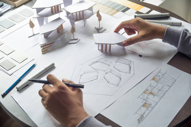istock architect design working drawing sketch plans blueprints and making architectural construction model in architect studio 1169087512