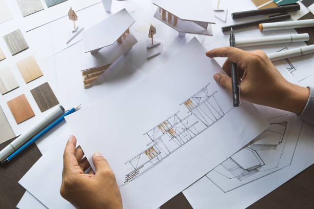 istock architect design working drawing sketch plans blueprints and making architectural construction model in architect studio 1169087513