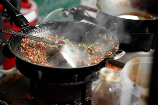 cooking Thai stir-fried minced pork with basil in the metal pan stock photo