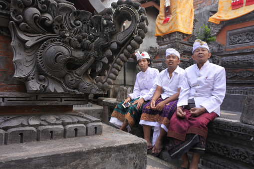 Three generation of Balinese men celebrating Galungan Kuningan holidays in a family temple in Ubud Bali, Indonesia.