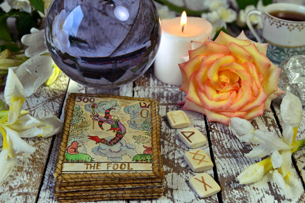 istock Tarot cards deck, crystal ball, runes and flowers on witch table. 1169092988