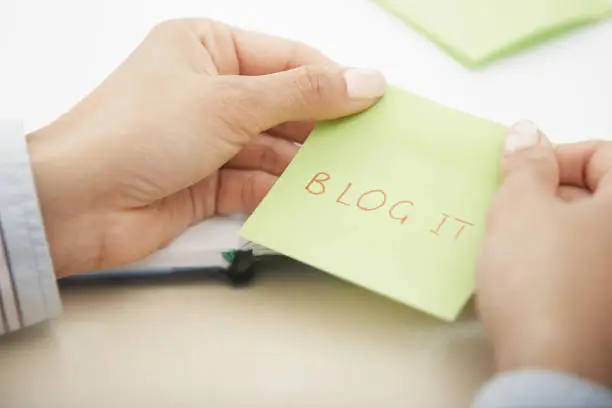 Photo of Hands holding sticky note with Blog it text