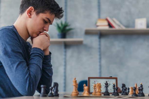 teenager-junge spielt schach allein - concentration chess playing playful stock-fotos und bilder