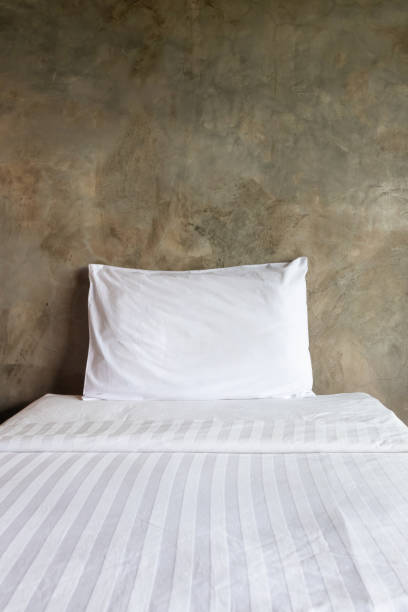 istock Pillows on comfortable bed with exposed concrete wall in modern bedroom. 1169095159