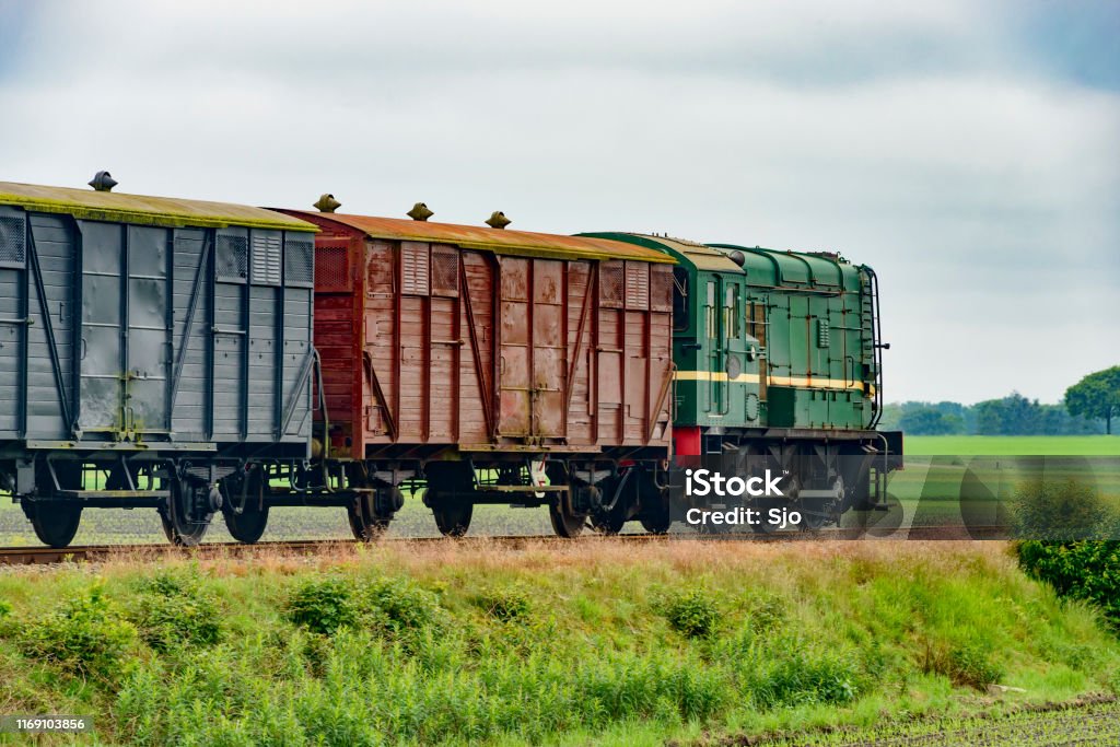 Old diesel freight train pulling various railroad cars in the countryside. Freight Train Stock Photo