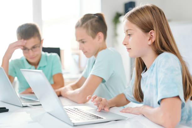istock Young serious schoolgirl and her classmates working individually 1169111126