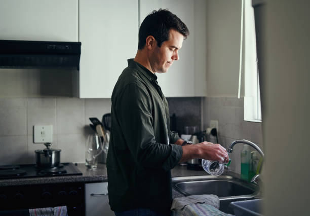 istock Man washing glassware in the kitchen sink 1169115940