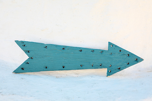 vintage, handmade, wooden arrow, with drilled holes and turquoise paint job pointing to the right