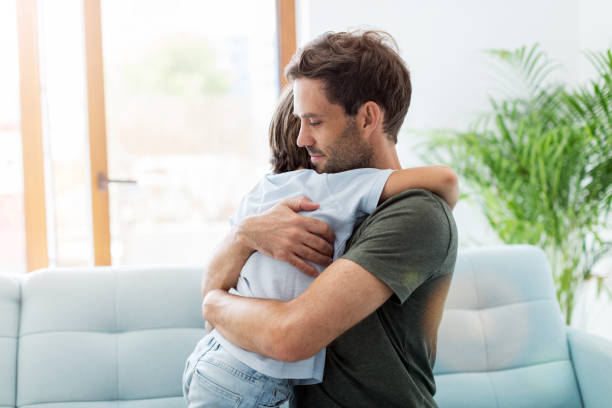 istock Father embracing son while sitting on sofa at home 1169122773